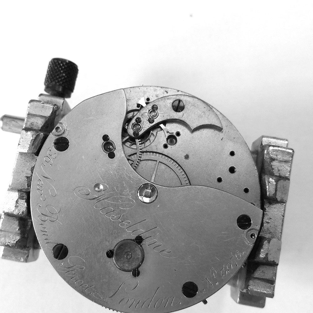 The Haseldine movement has a broken balance staff, and the balance wheel and bridge are removed.